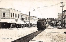 J47/ Iola Wisconsin RPPC Postcard c1910 Trolley Stores Main Street 259 picture